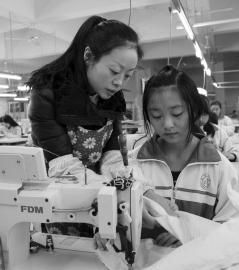 大英縣中等職業技術學校內，企業服裝技師正指導學生進行縫紉操作。